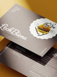 Vorder- und Rückseite der Kontaktpostkarte LechBiene, platziert auf gelben Hintergrund.